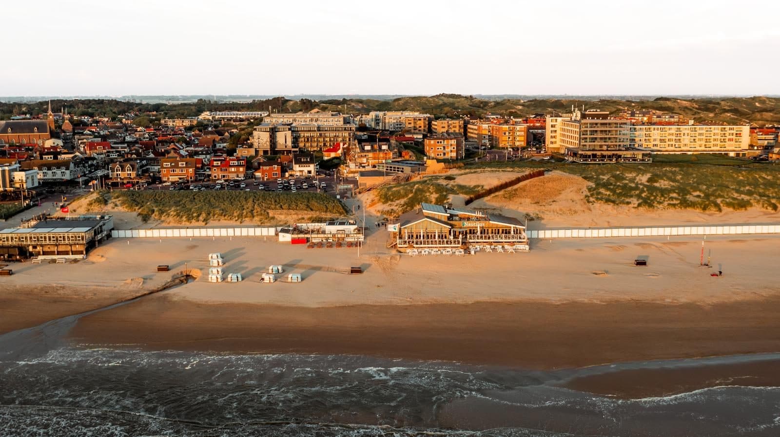 Aerial view of Egmond aan Zee: beach, beach pavilions, boulevard and village