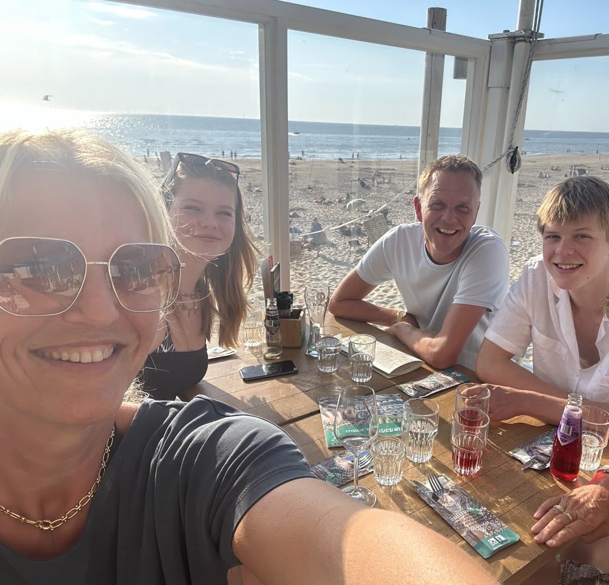 The family at a beach pavilion table, with Egmond beach in the background